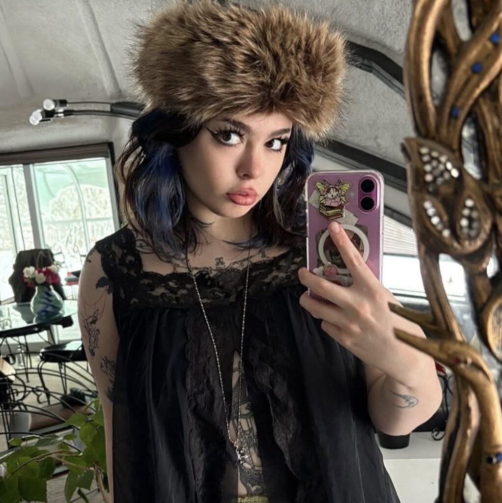 The Thundermans star Addison Riecke takes a mirror selfie wearing a fur hat in 2026.