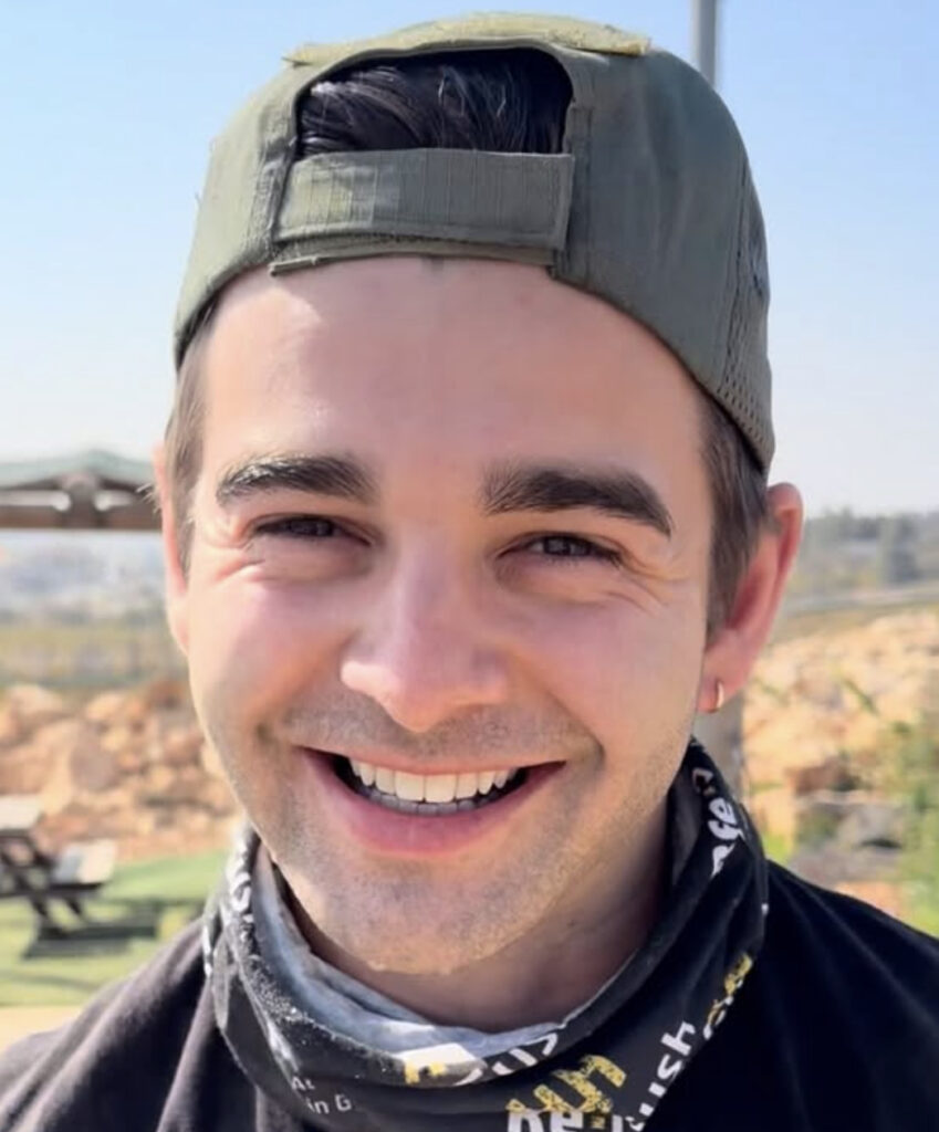 Jack Griffo from The Thundermans wearing a backwards hat and smiling in a 2026 photo with a scenic background