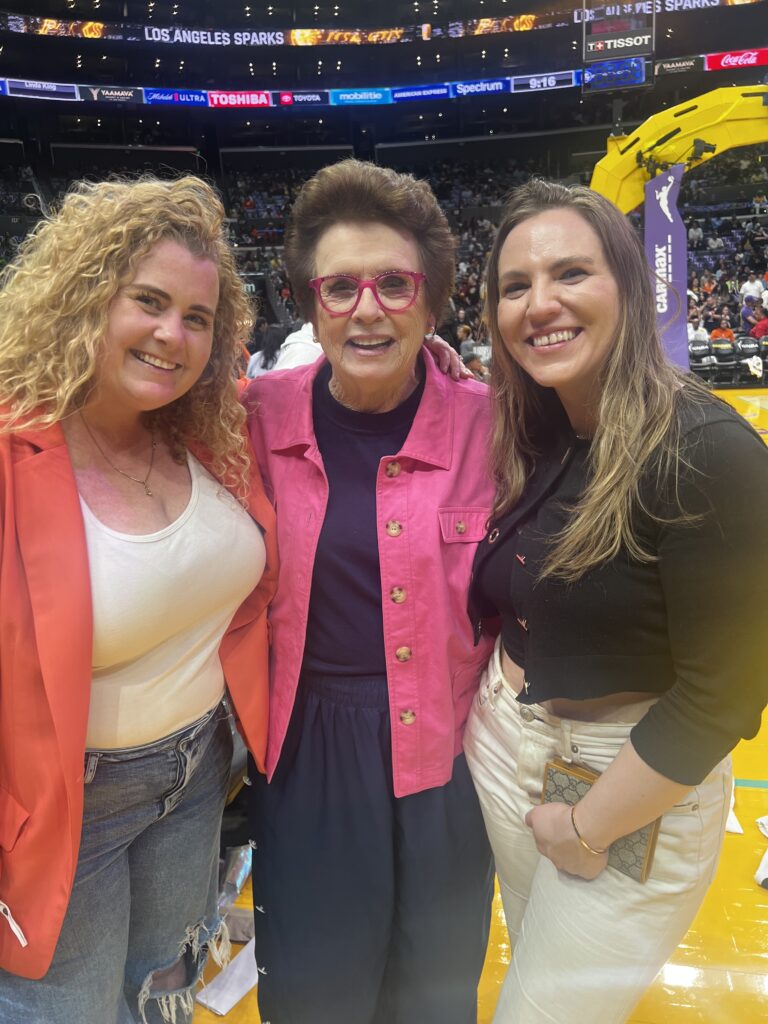 Colleen Broomall, Natasha Dye and Billie Jean King smiling for a photo while courtside at a Los Angeles Sparks game